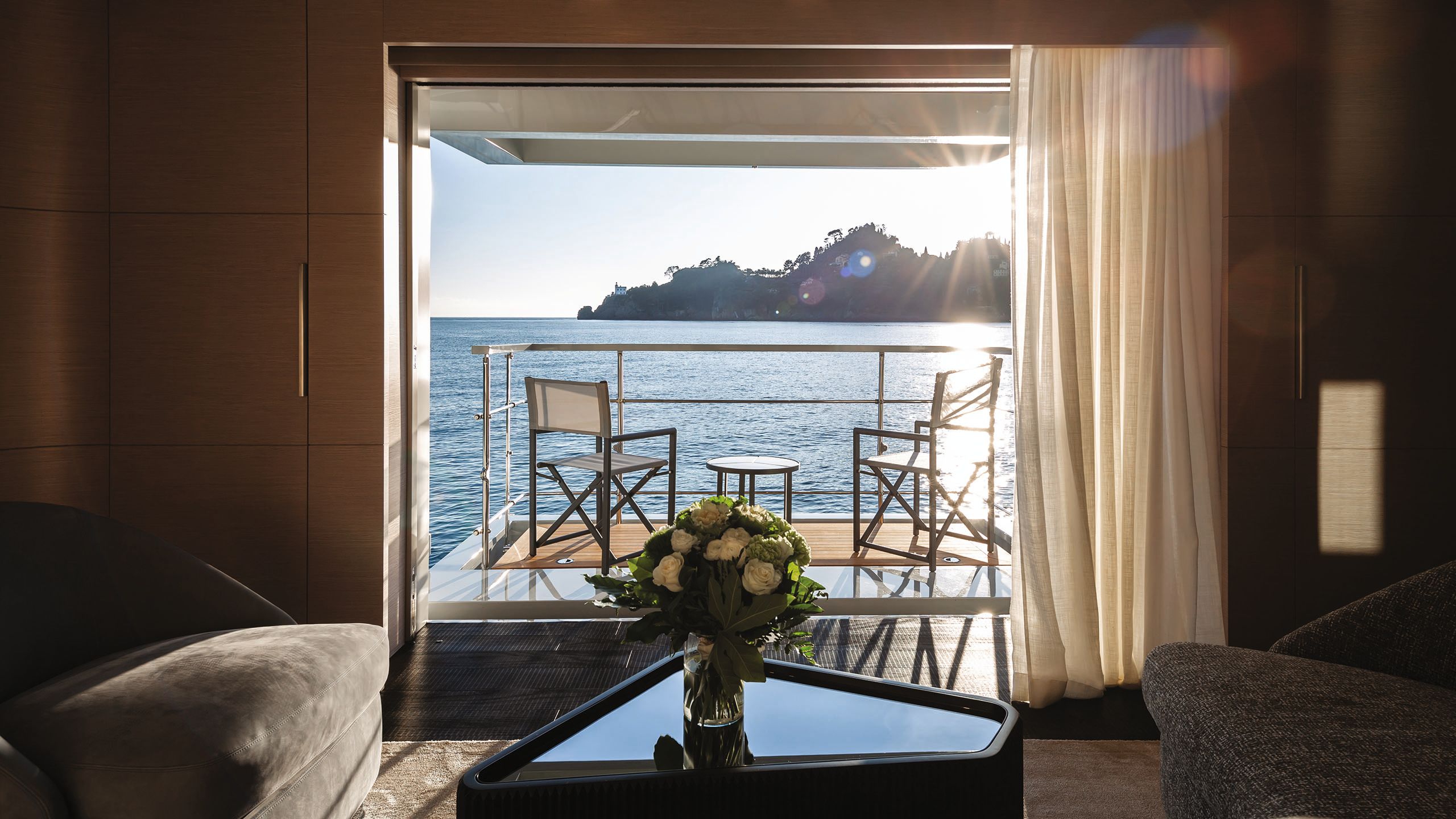 Looking out of the cabin on to a balcony which has two chairs and a table on it