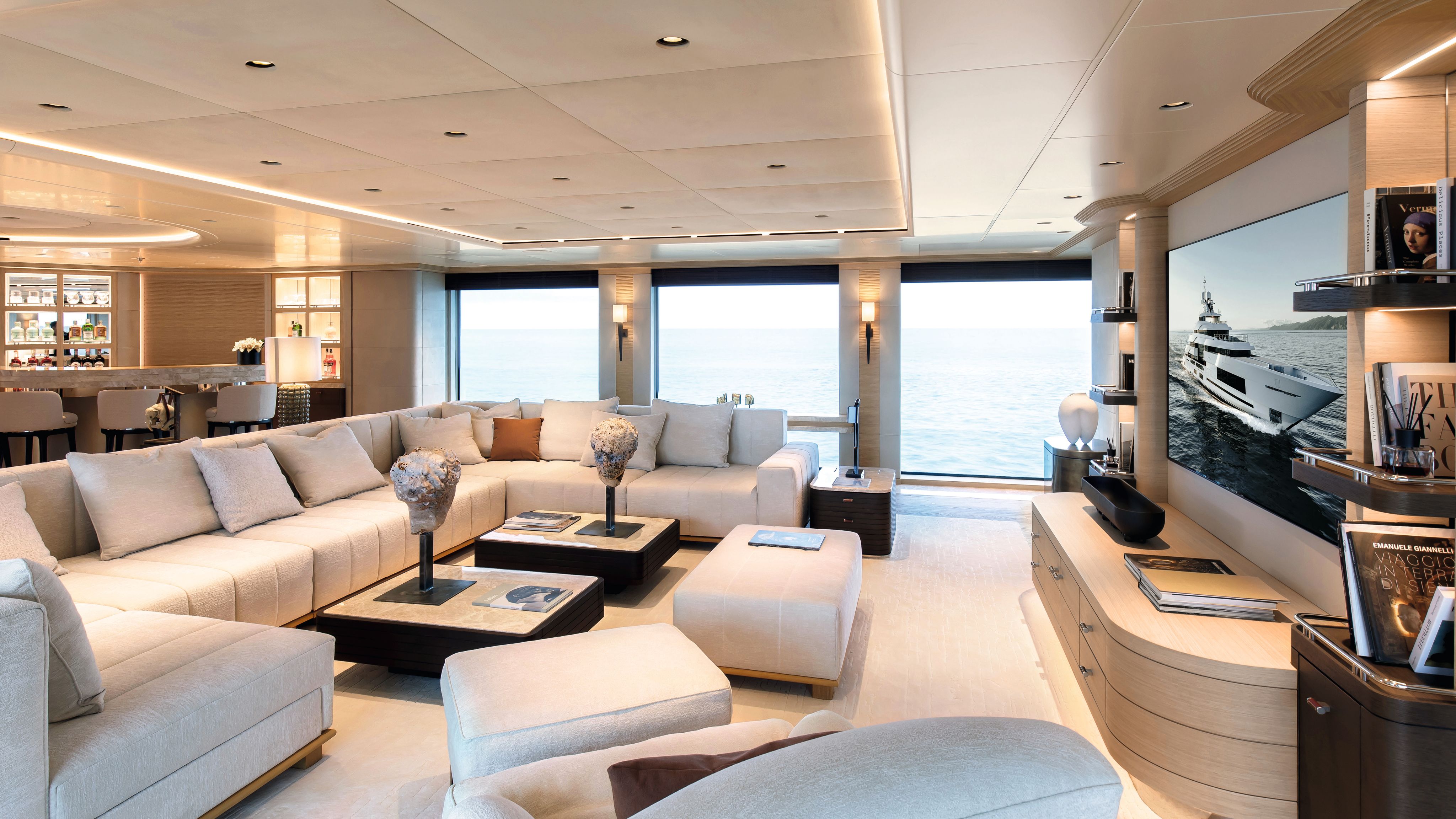 Alt view of the living room area which has a U-shaped grey sofa, mayching footstools and two dark brown coffee tables 