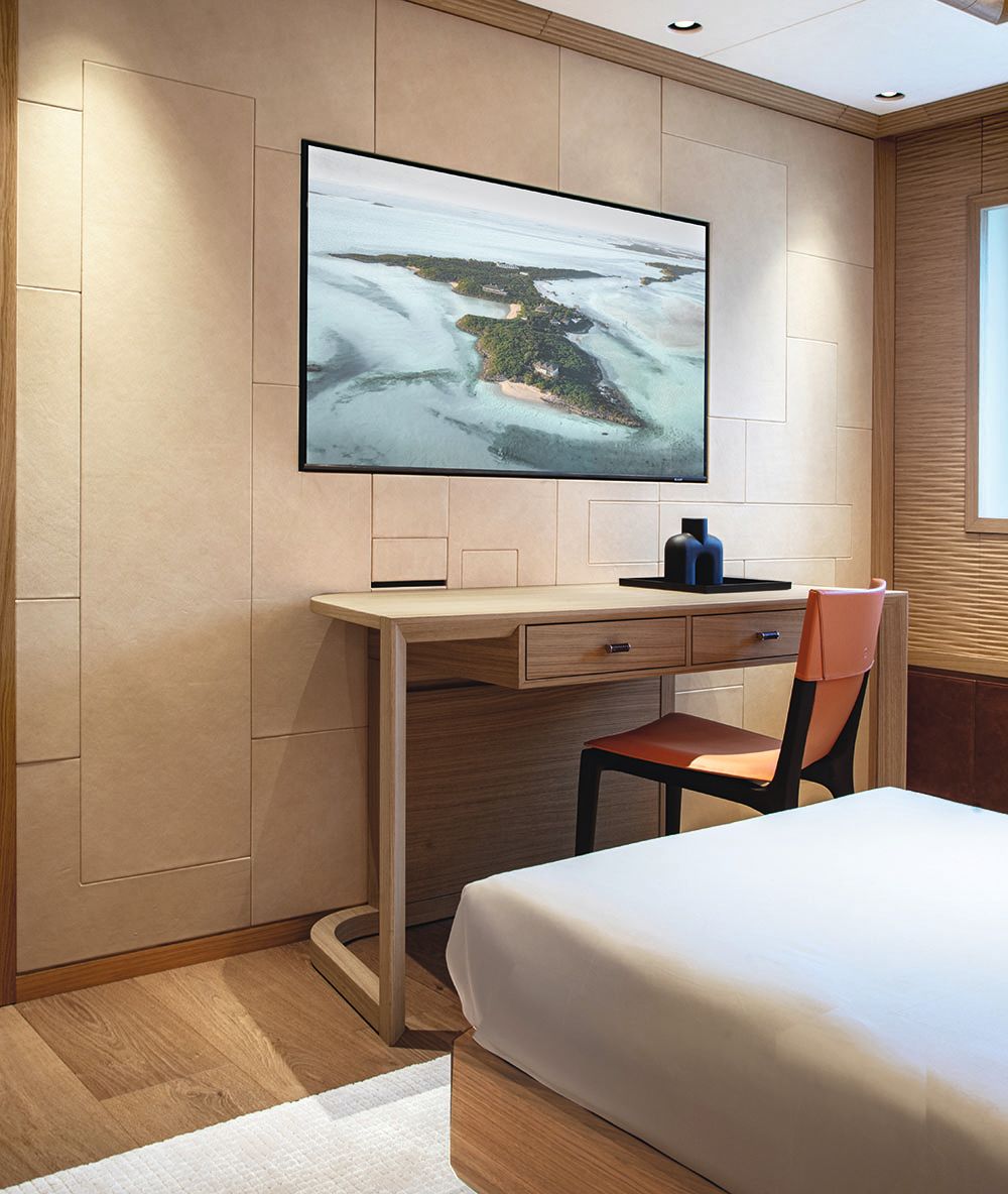 A desk and chair at the foot of a bed