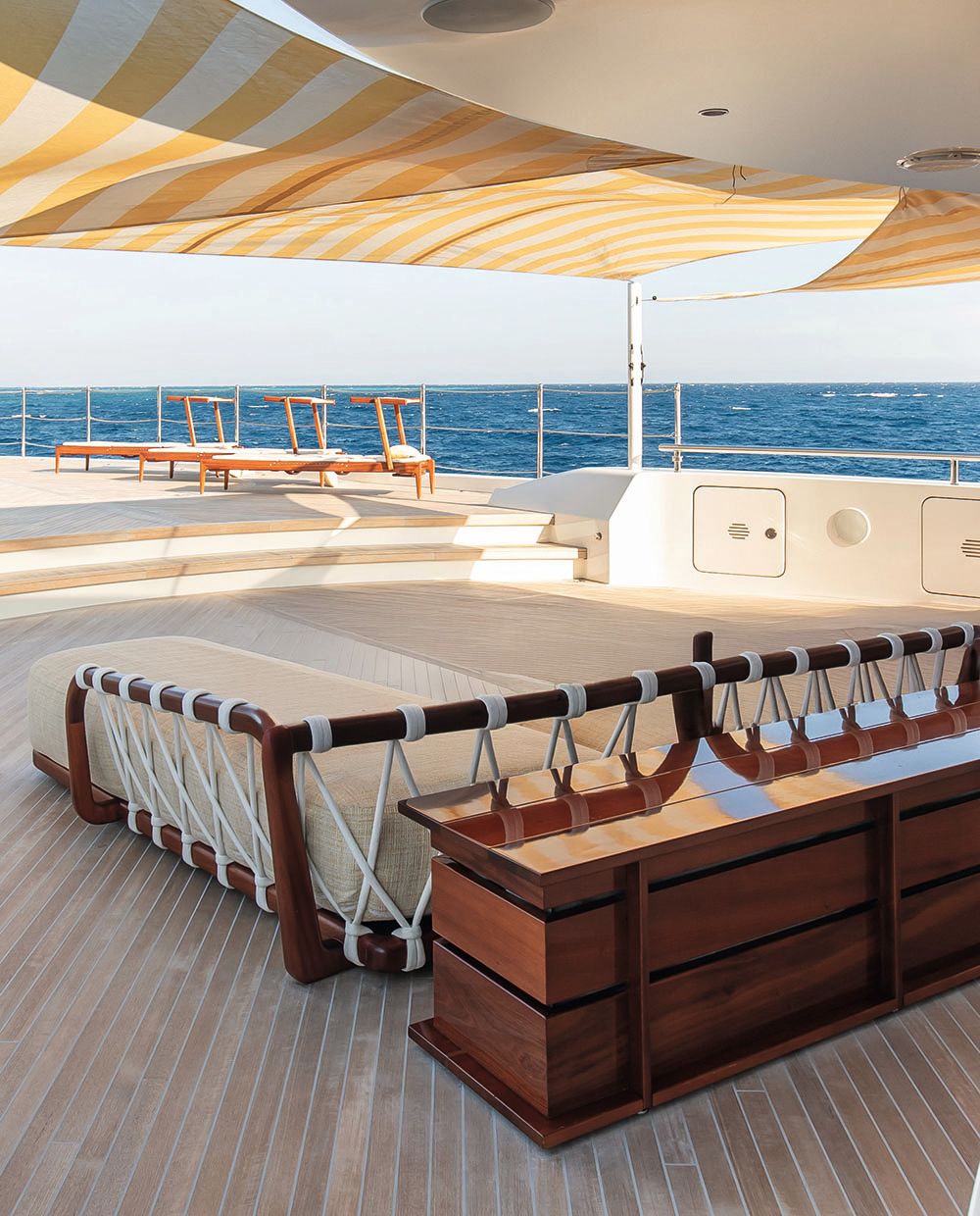 Close-up of a long cream soft seat with teak rail and rope effect wrapped around the frame