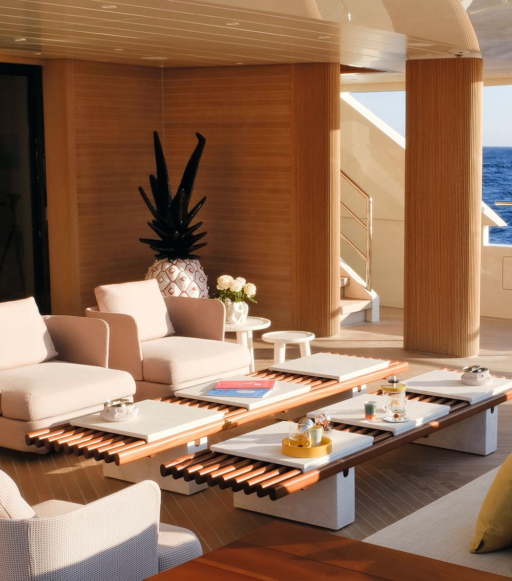 Close-up on the teak table and white armchairs that face out on to the deck