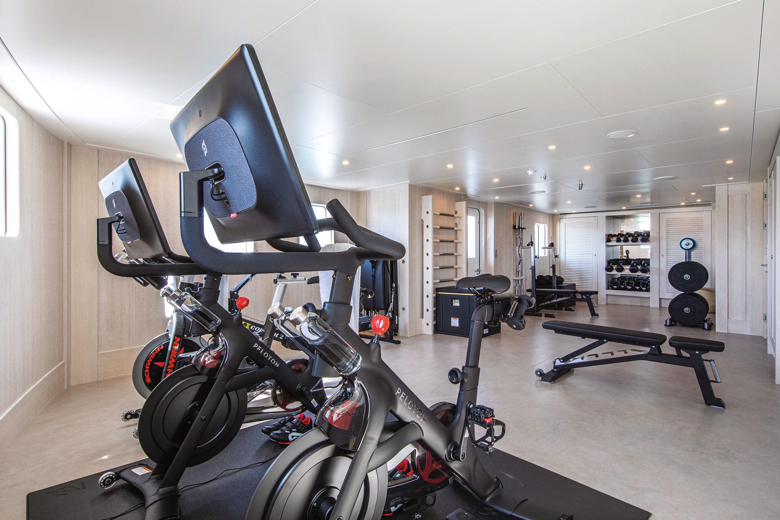 Wide shot of the gym showing Peleton bikes, an exercise bench and weights in the background