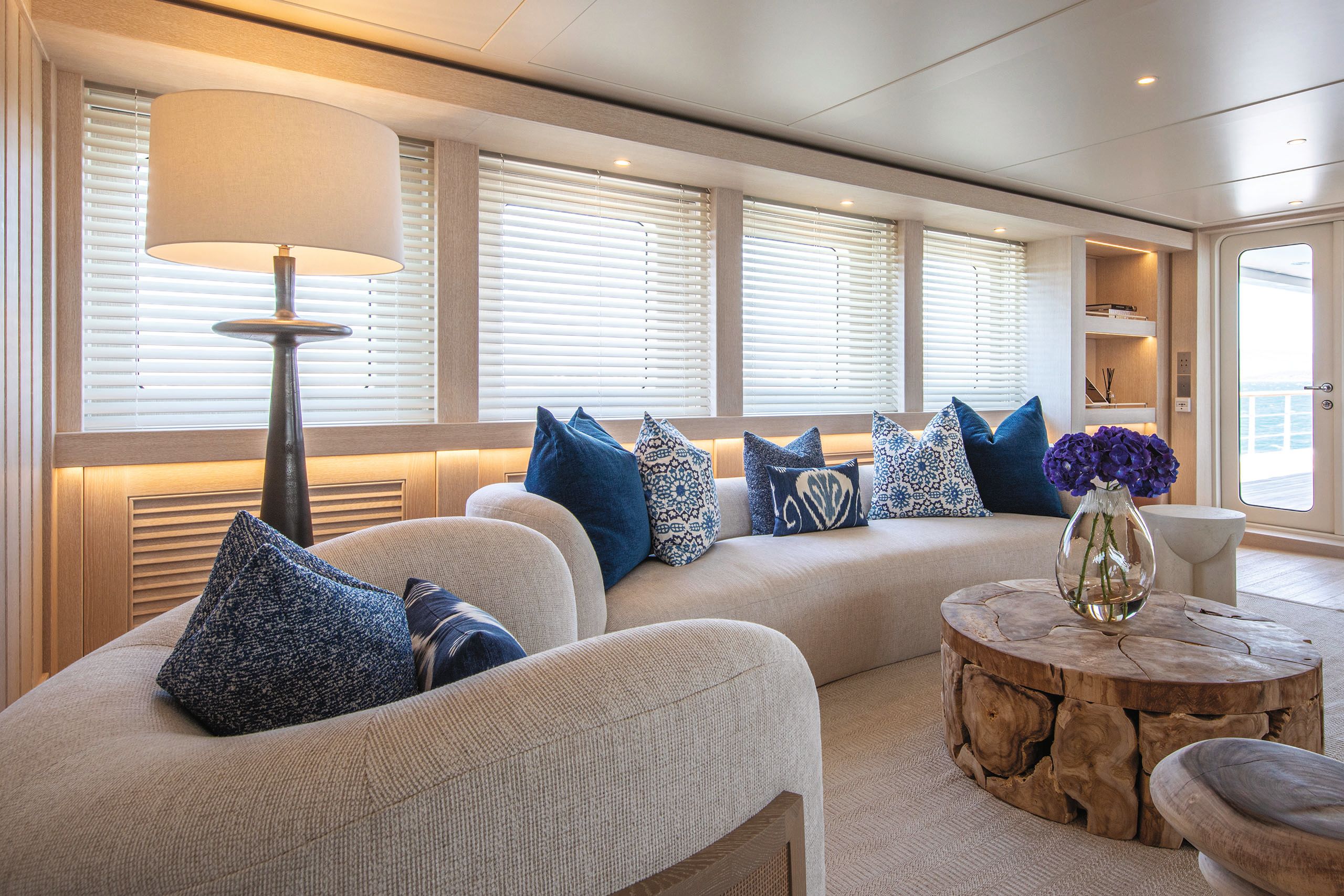 Curved beige sofas with blue cushions and a round wooden coffee table