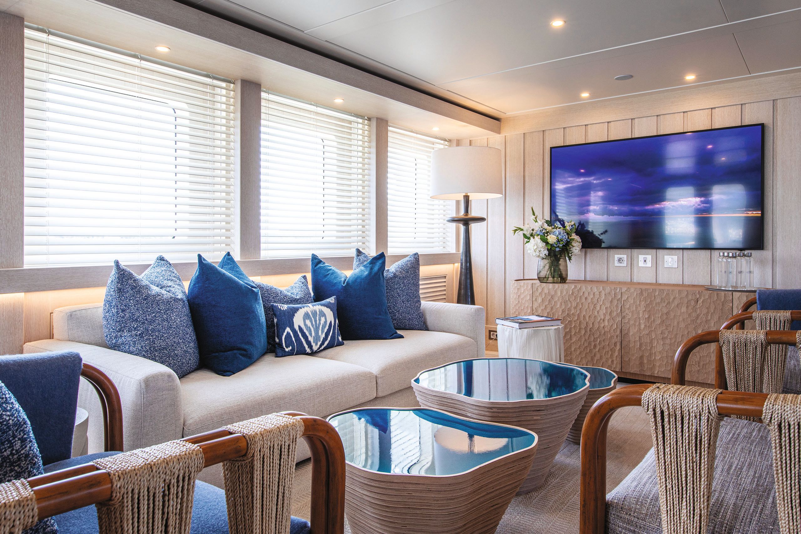 Close up of sofa covered with several blue cushions. The coffee tables in front also have blue inlays.