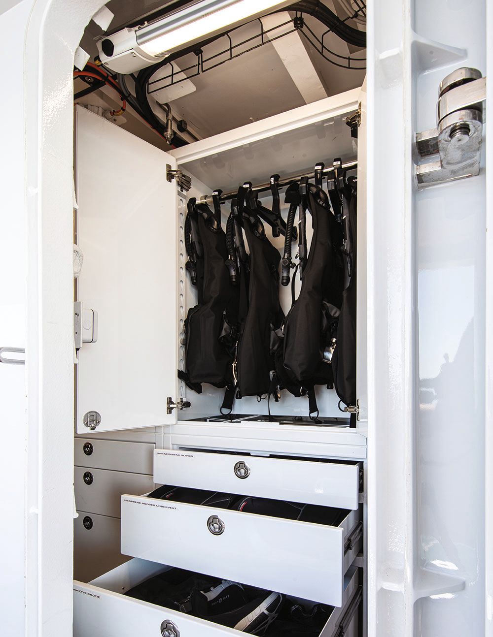 Scuba diving equipment hanging in a cupboard that has drawers underneath