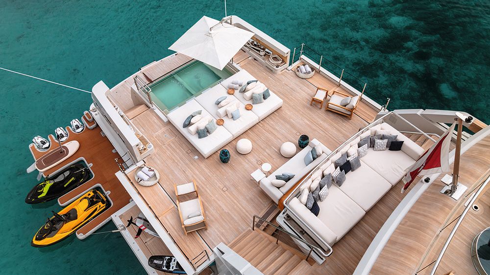 Large deck space with pool, loungers, sofa and loose furniture. To the left are water toys