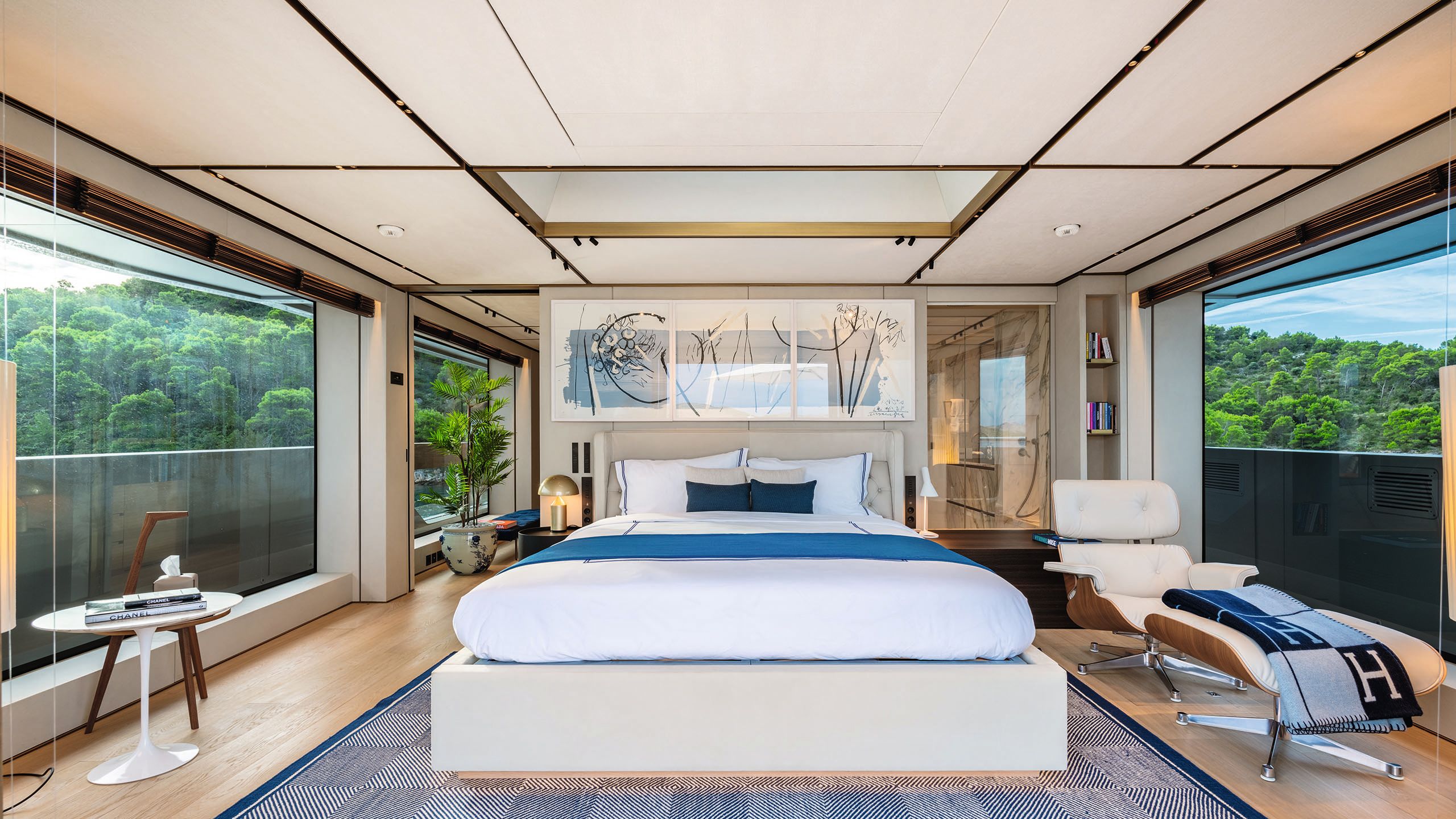 Alternative view of the owner's suite, looking directly at the bed. It has abstract white and blue art over the headboard and a large, leather reclining chair and footstool to the right