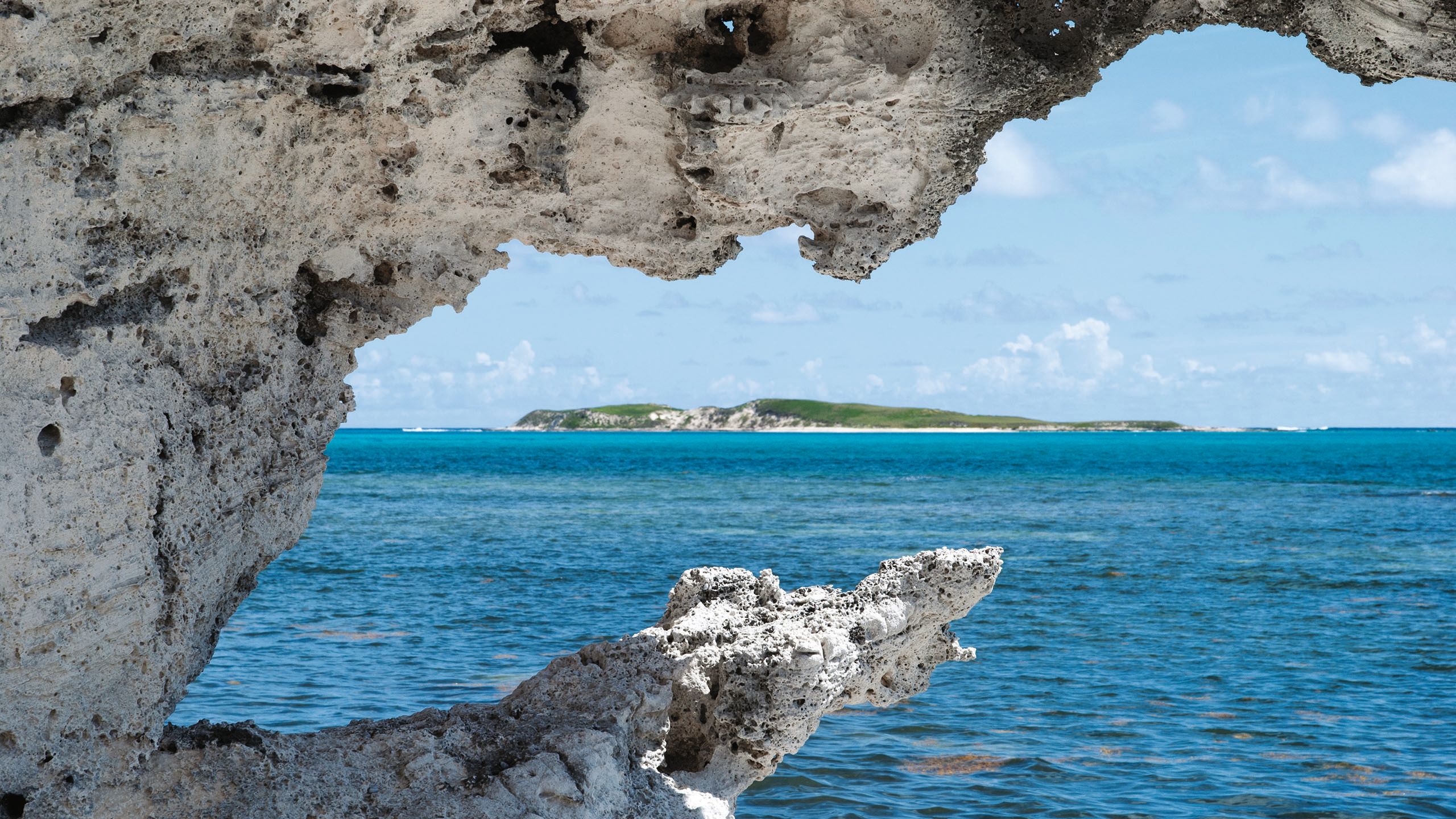 Turks and Caicos as taken from far away under a stone arch, the sea in the middle ground
