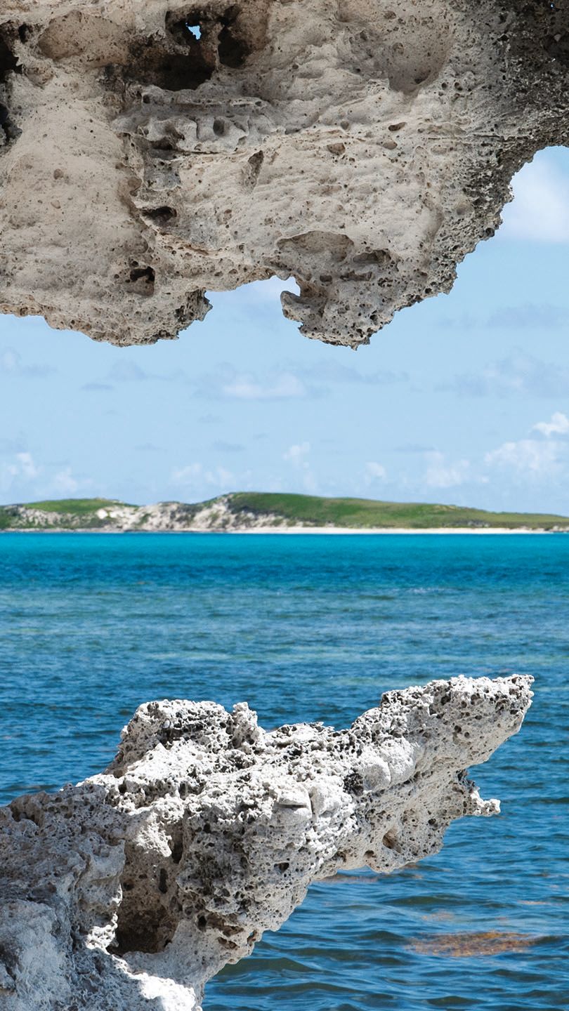 Turks and Caicos as taken from far away under a stone arch, the sea in the middle ground