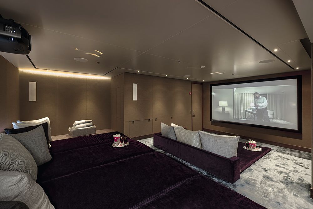 Sofas facing a cinema screen at the front of the room