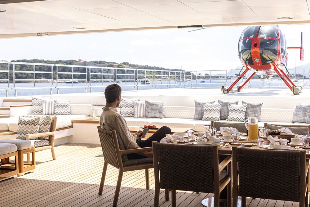 The back of a man who is sitting at the dining table in a chair and looking out at the helicopter