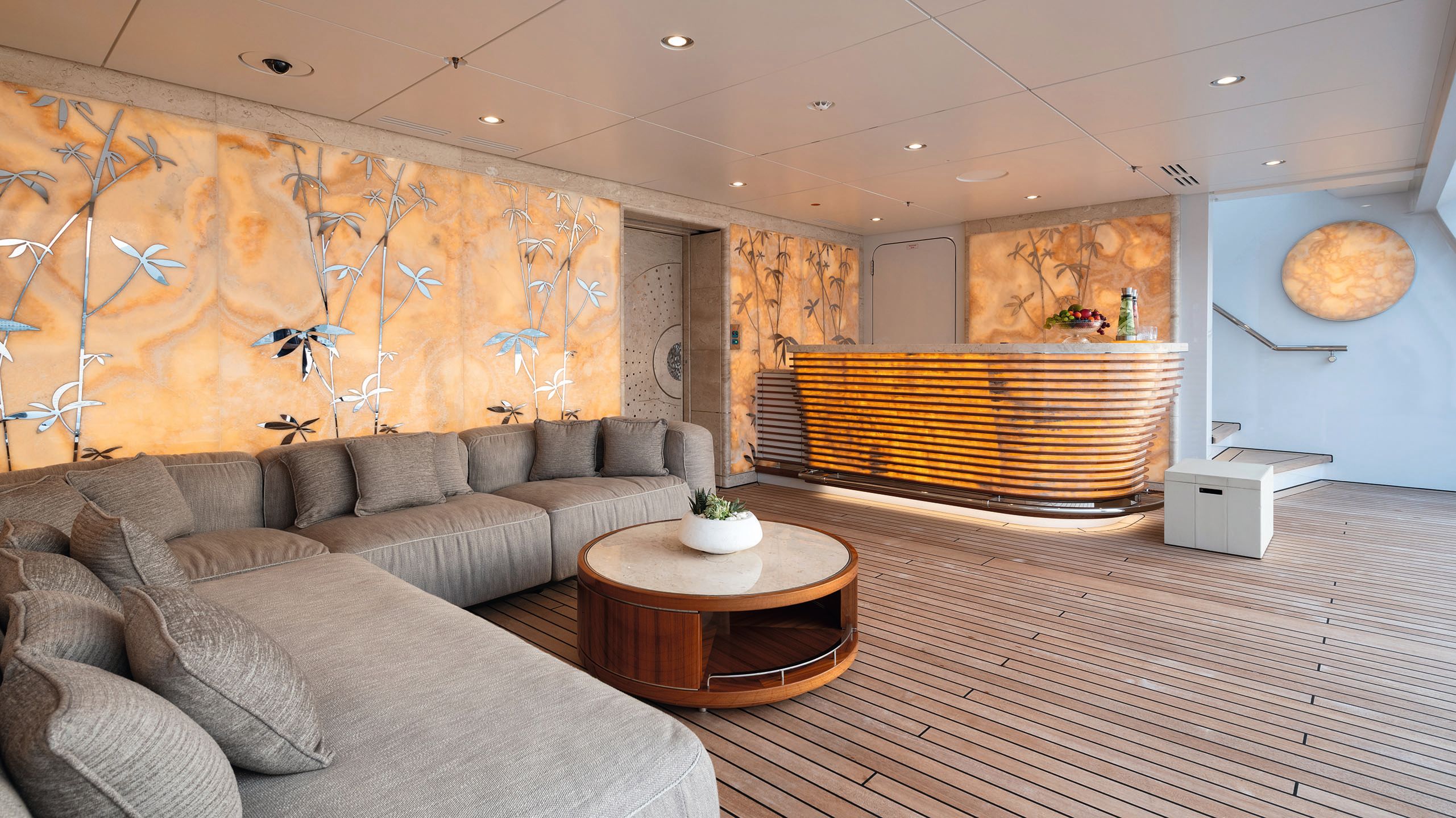 A close-up of the interior of the beach club which has a large L-shaped sofa in grey and a corner bar