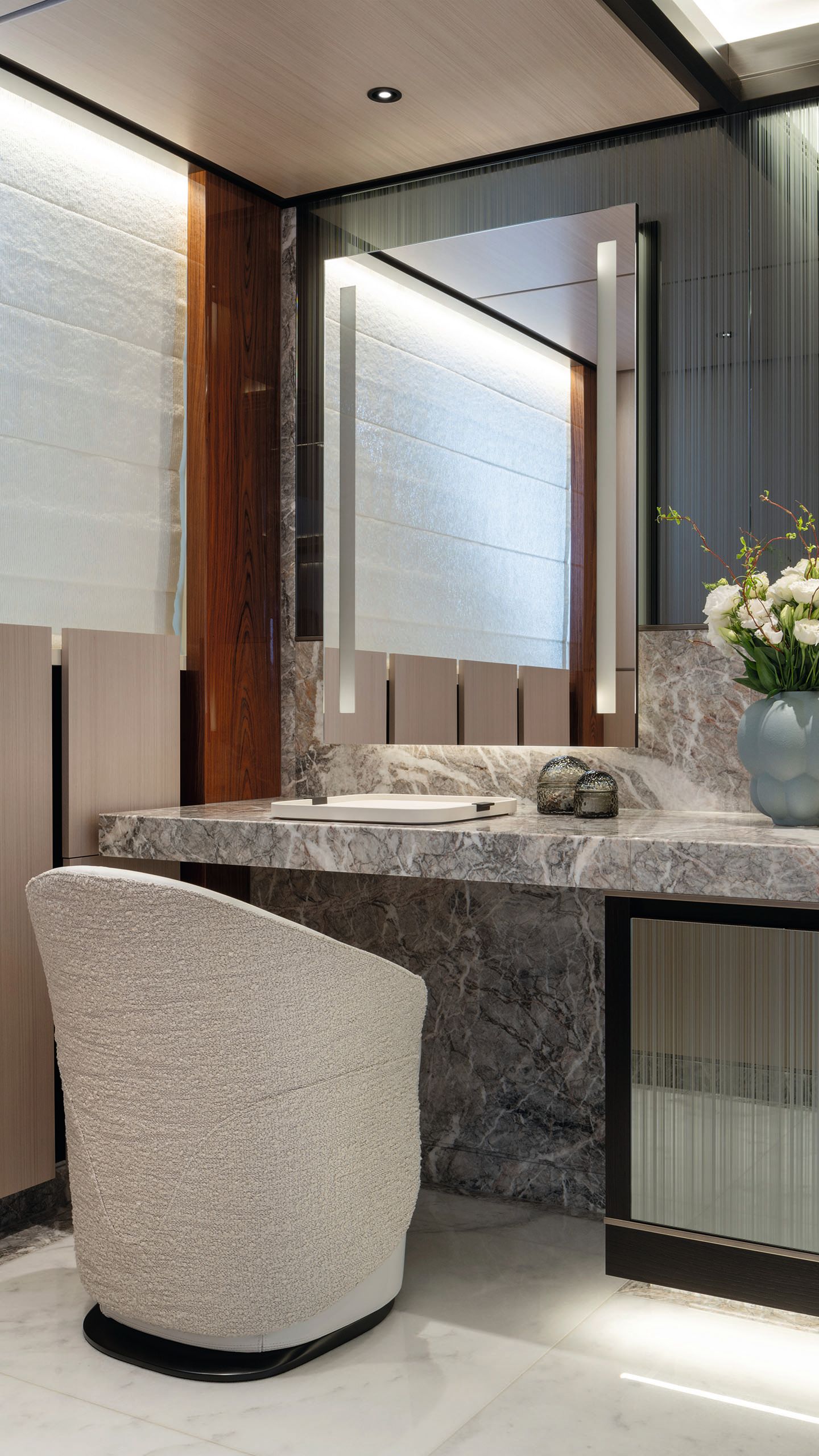 The vanity area has a marble counter and white armchair