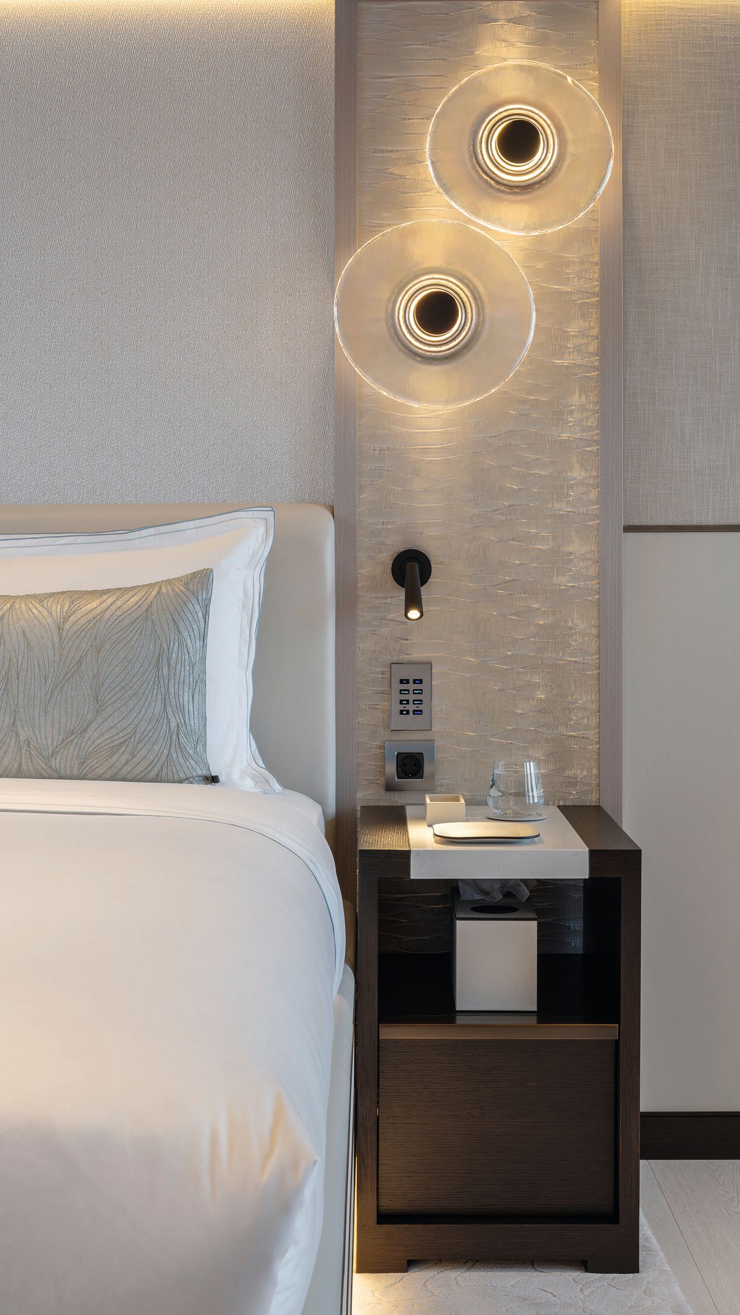 Partial straight-on view of the side of a bed with bedside table to the right