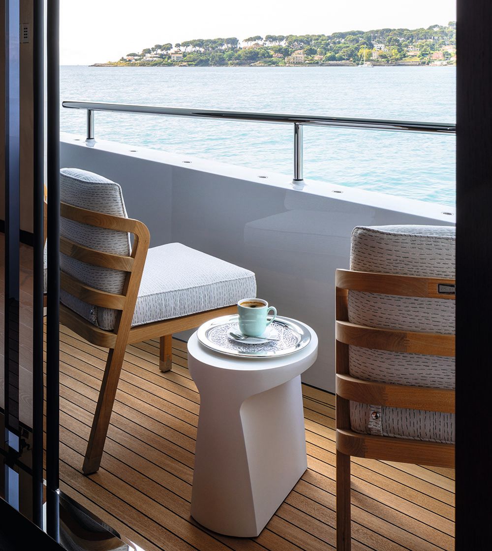 Looking out on to the side balcony where there are two armchairs and a small table inbetween