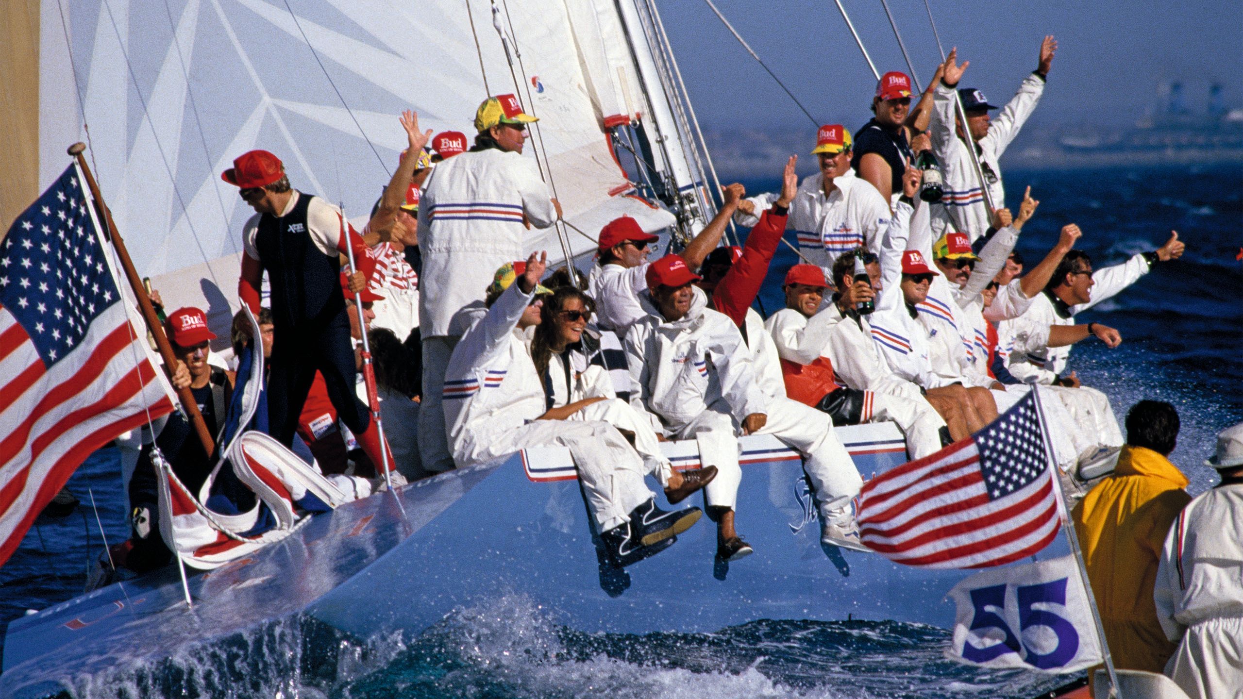 Large crew of people celebrating with their hands up in the air on a vessel