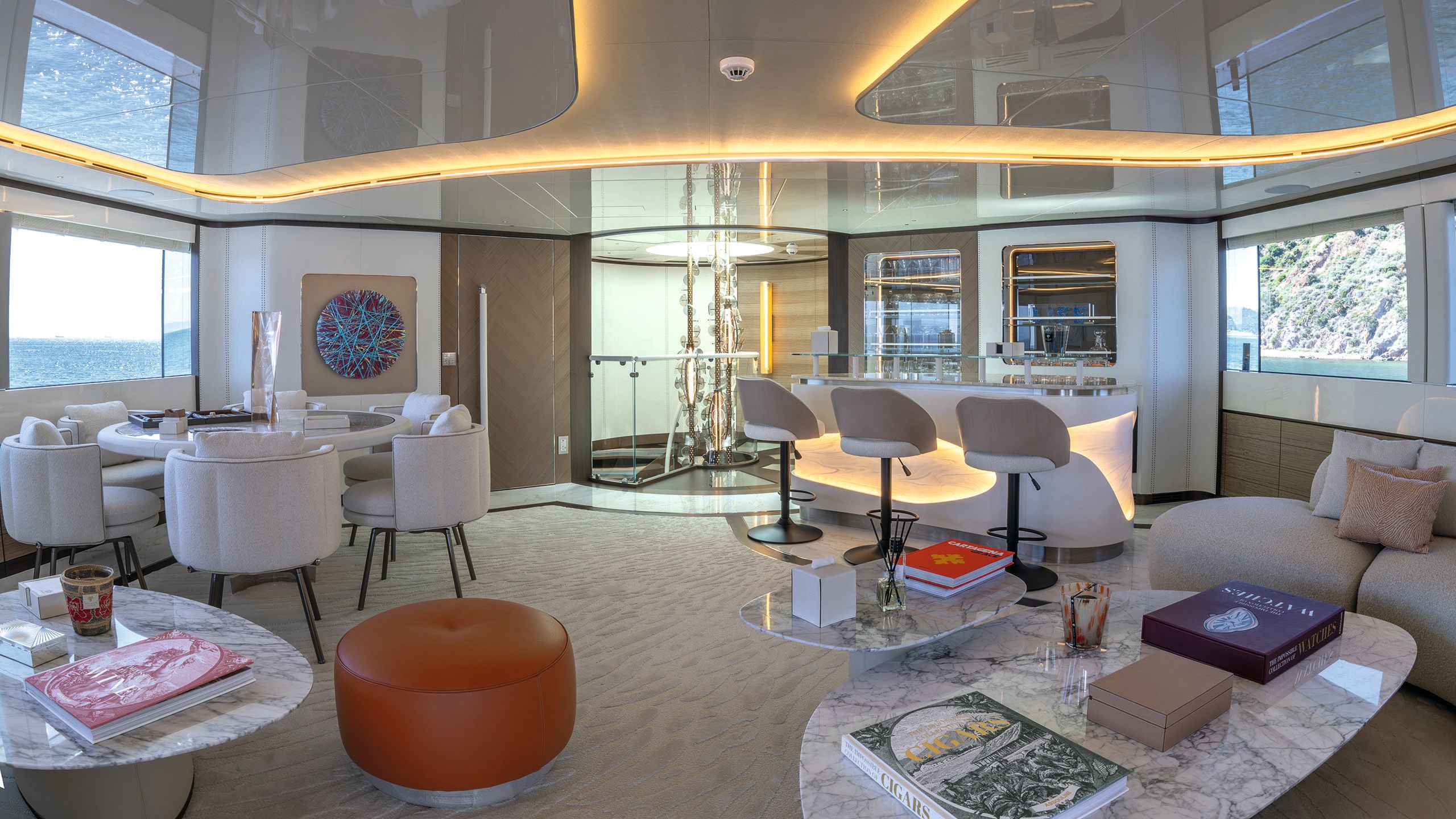 Two small marble-topped coffee tables in the foreground, a small round dining table with chairs to the left and a bar counter and high stools to the right