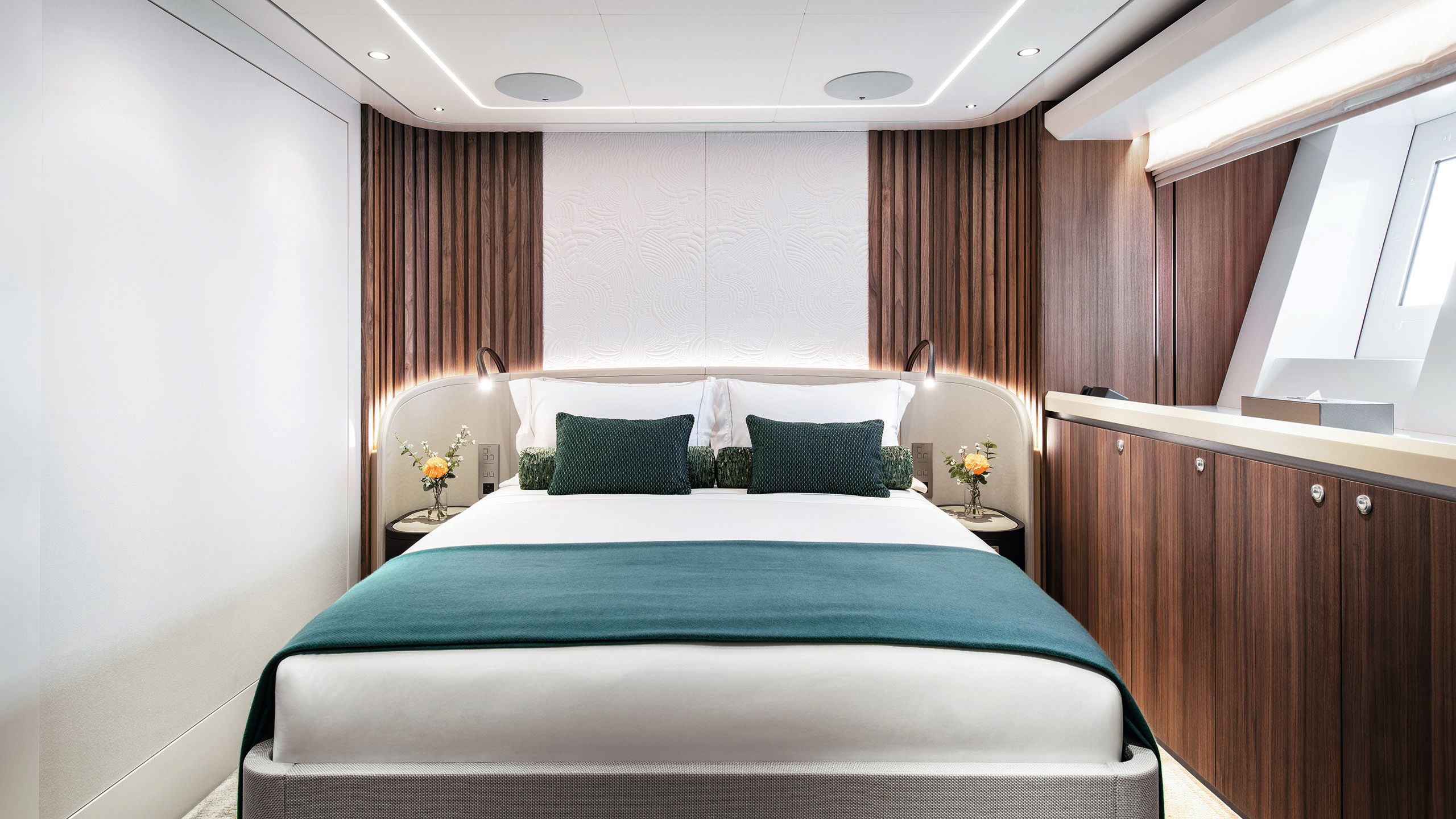 The double bed in the guest suite has white linens and teal blankets and cushions