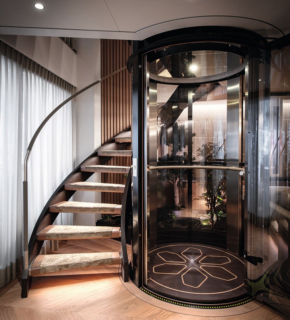 View of a staircase curving around an elevator with glass doors