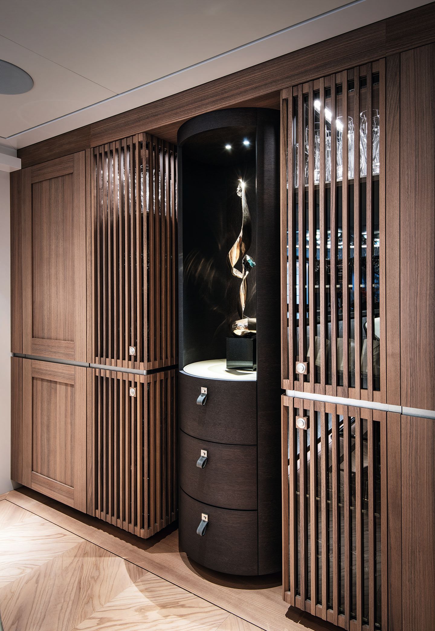 The wine cabinet is made of walnut and has ribbed doors