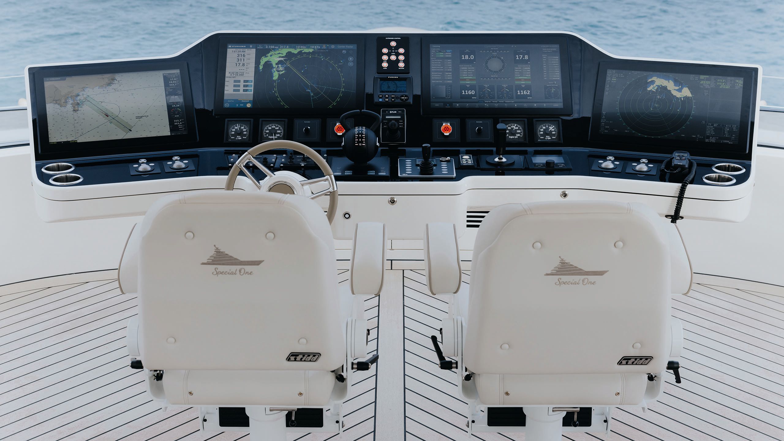 Two white leather seats from behind, facing a steering wheel and large control panel with screens
