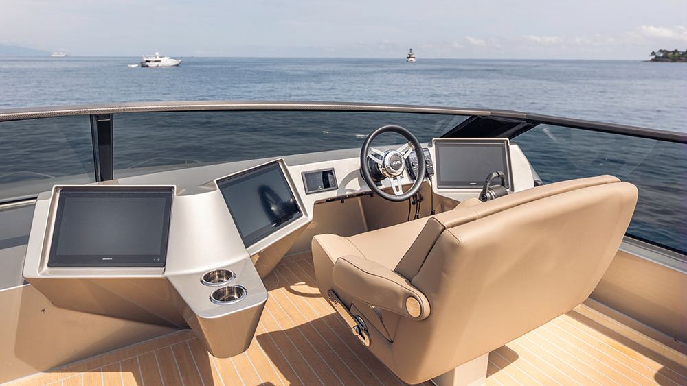Light camel-coloured chair in front of a wheel and two screens