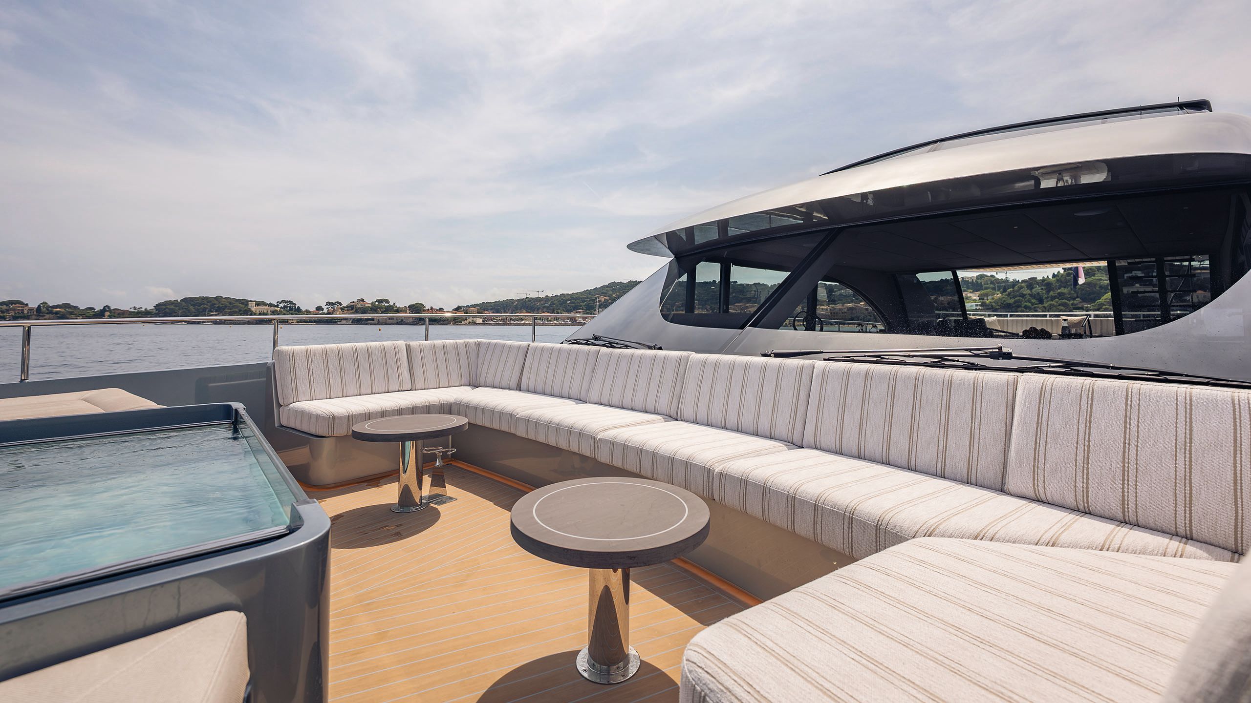 Outdoor deck with large c-shaped banquette sofa opposite the glass-sided pool