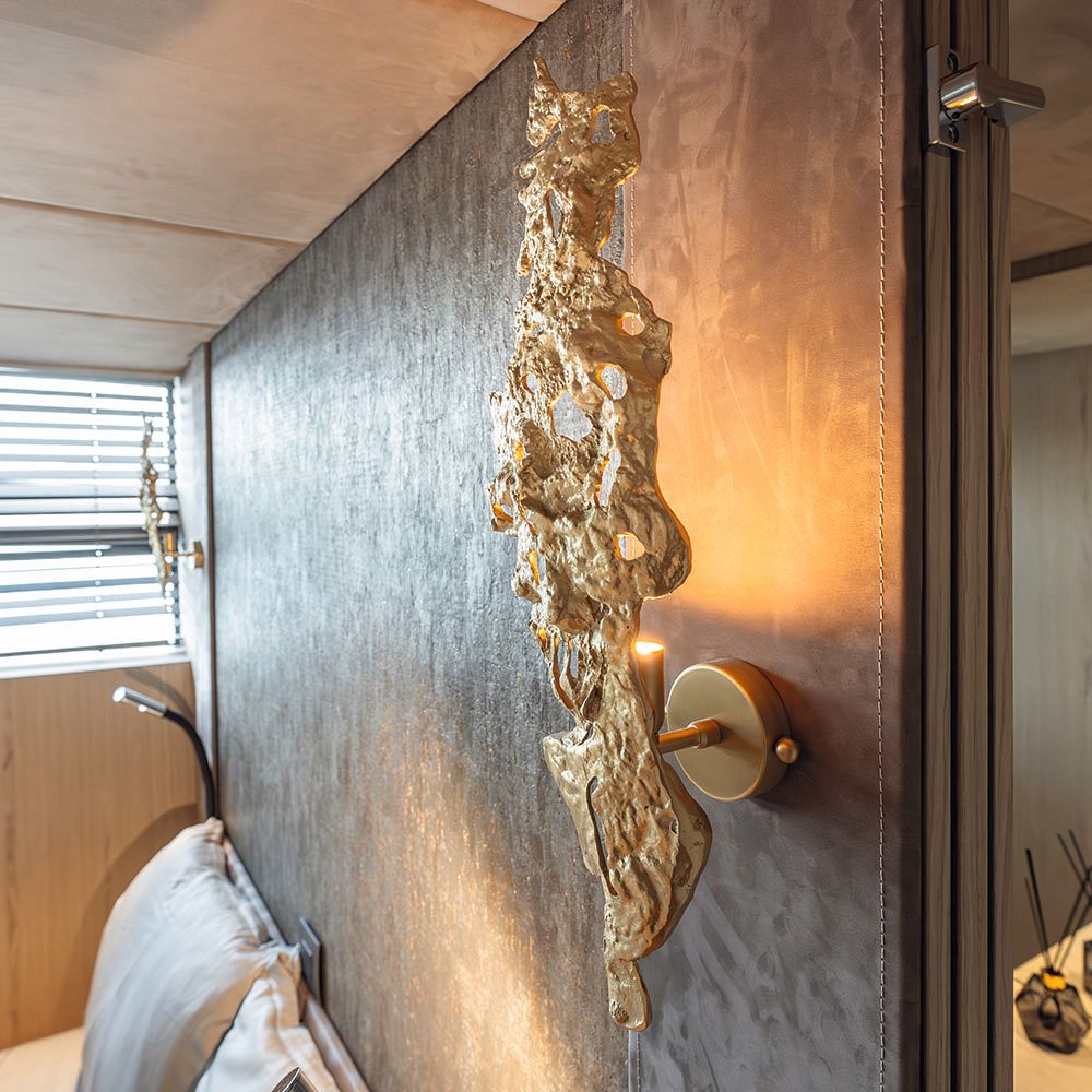 Close-up of an abstract gold-coloured lamp on a bedroom wall