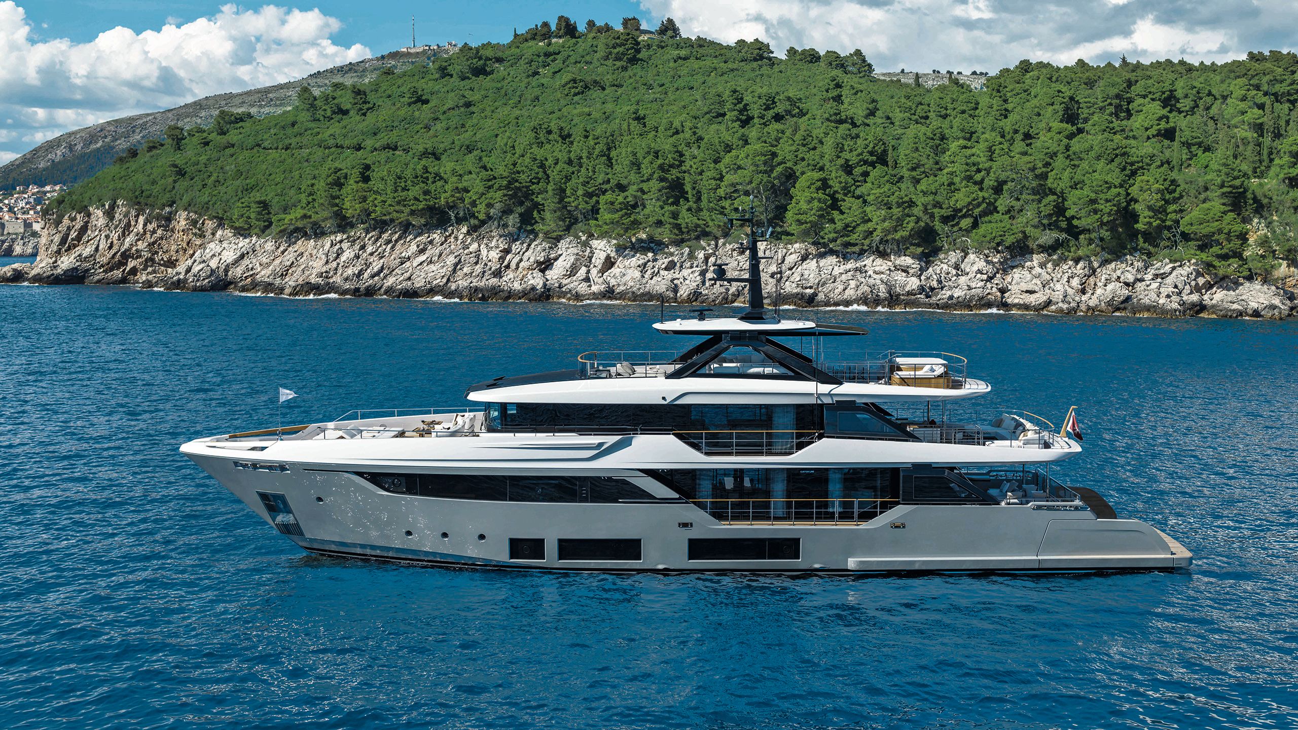 Side view of Navetta 38 with rocky coastline and forest behind