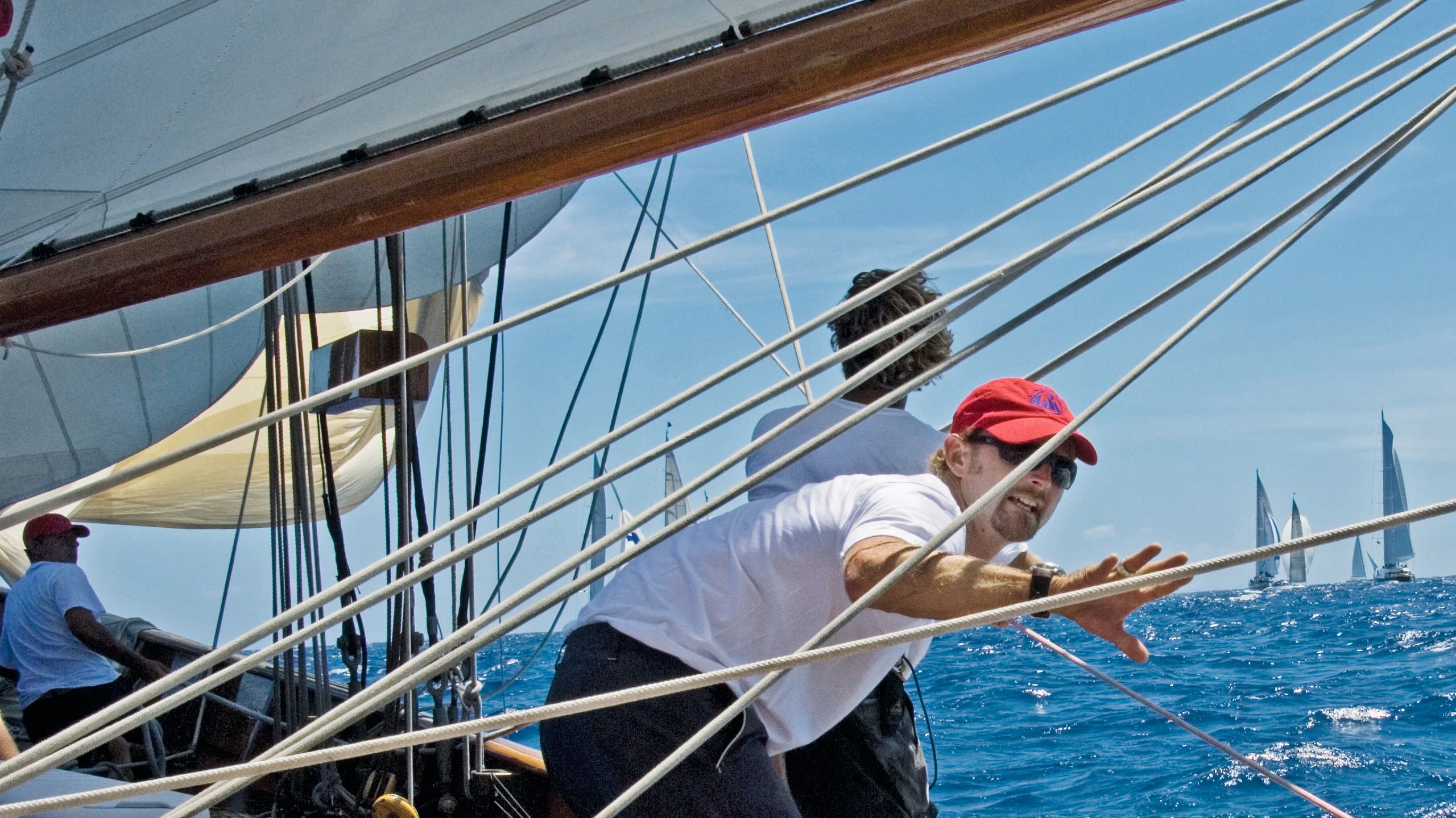 Close-up of a man on a sailboat wearing a red cap