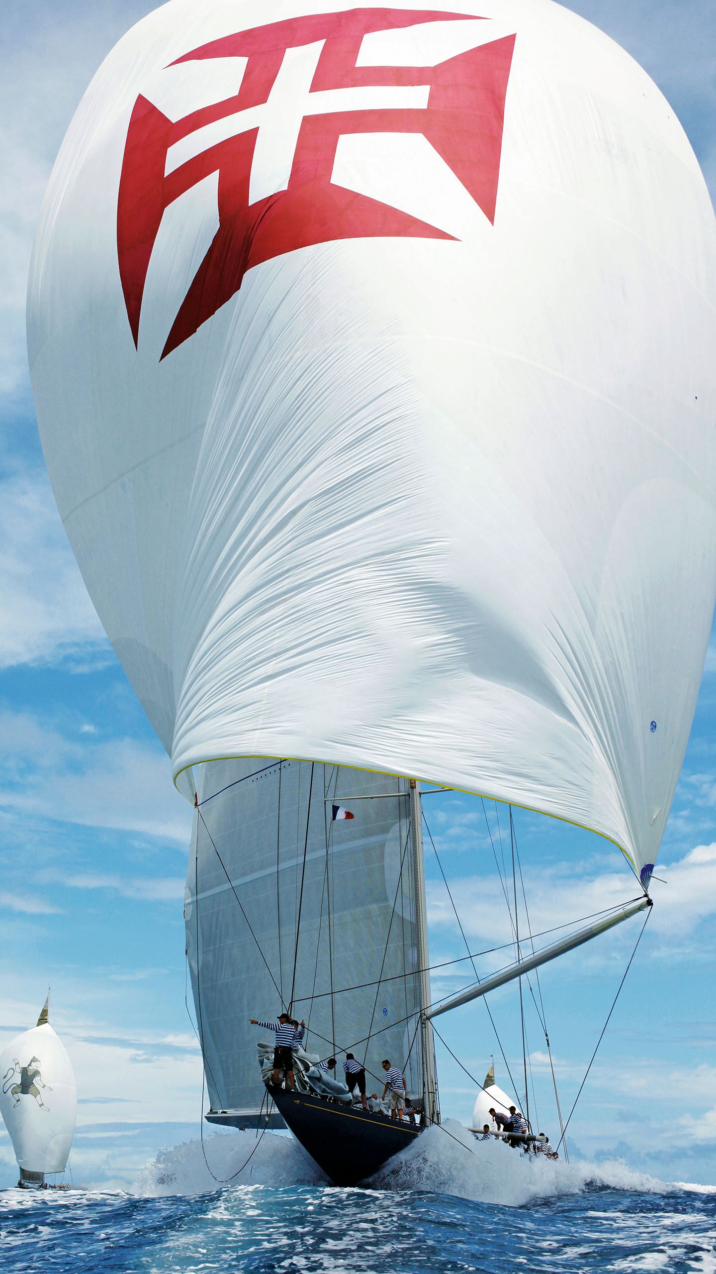 A sailboat with a large white sail and red cross on it