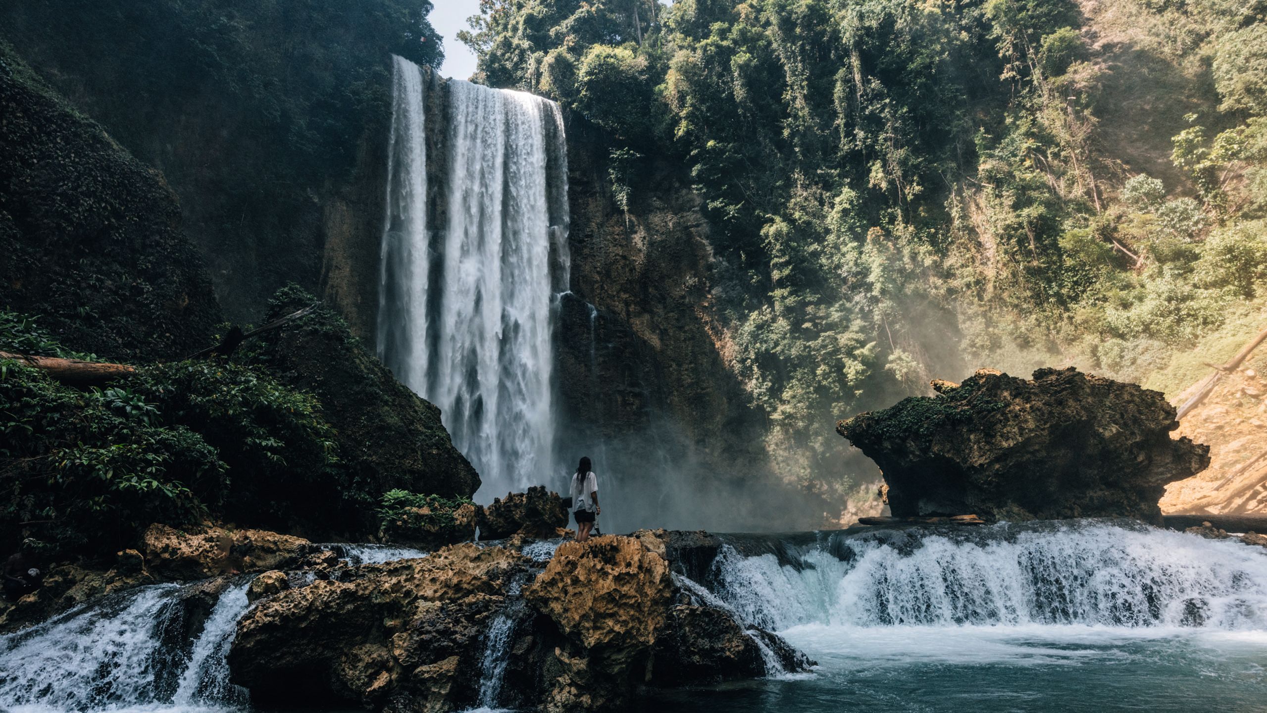 A woman walking near a waterfall