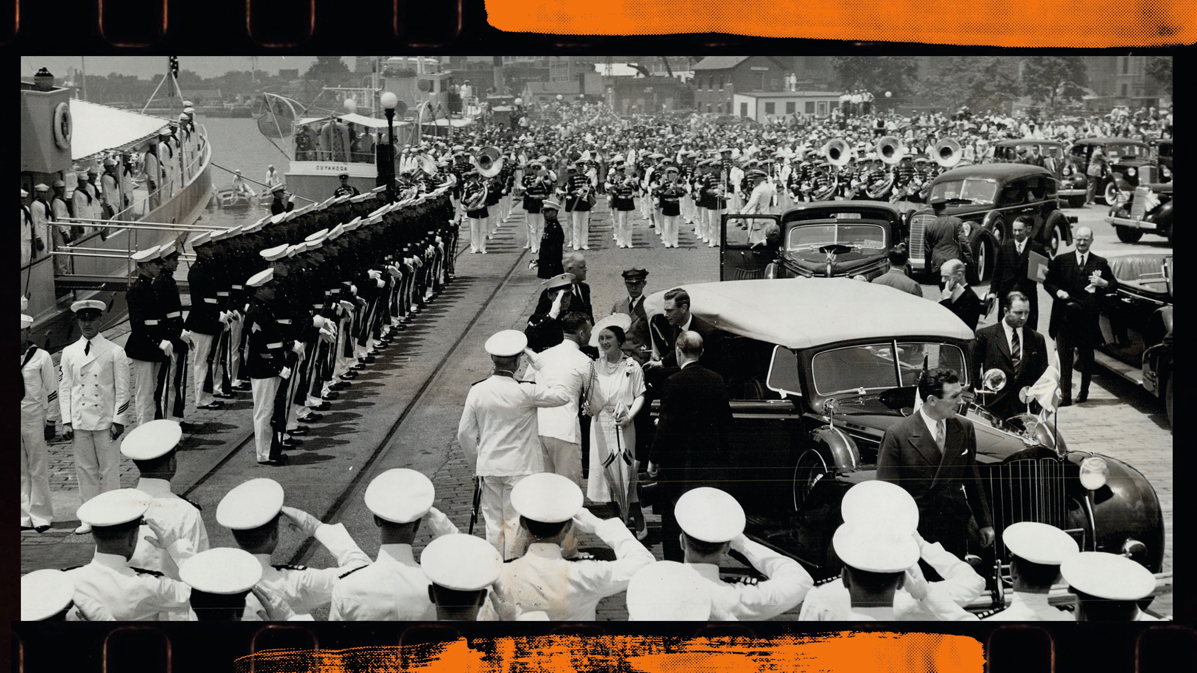 A wide shot of servicemen in white uniforms and hats saluting the King and Queen as they get out of a black car with a white top. There are servicemen on all sides standing to attention and some are holding guns while others play brass instruments